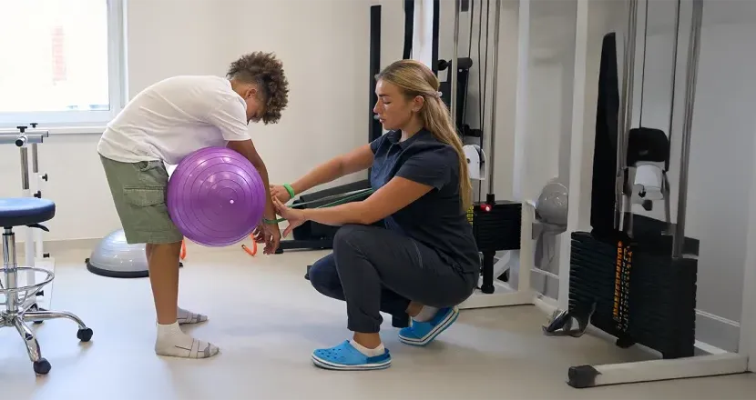 A physical therapist assistant working with a child in a rehabilitation setting, demonstrating hands-on training in Herzing University’s Physical Therapist Assistant program.